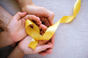 adult and child hands holding yellow gold ribbon, Sarcoma Awaren
